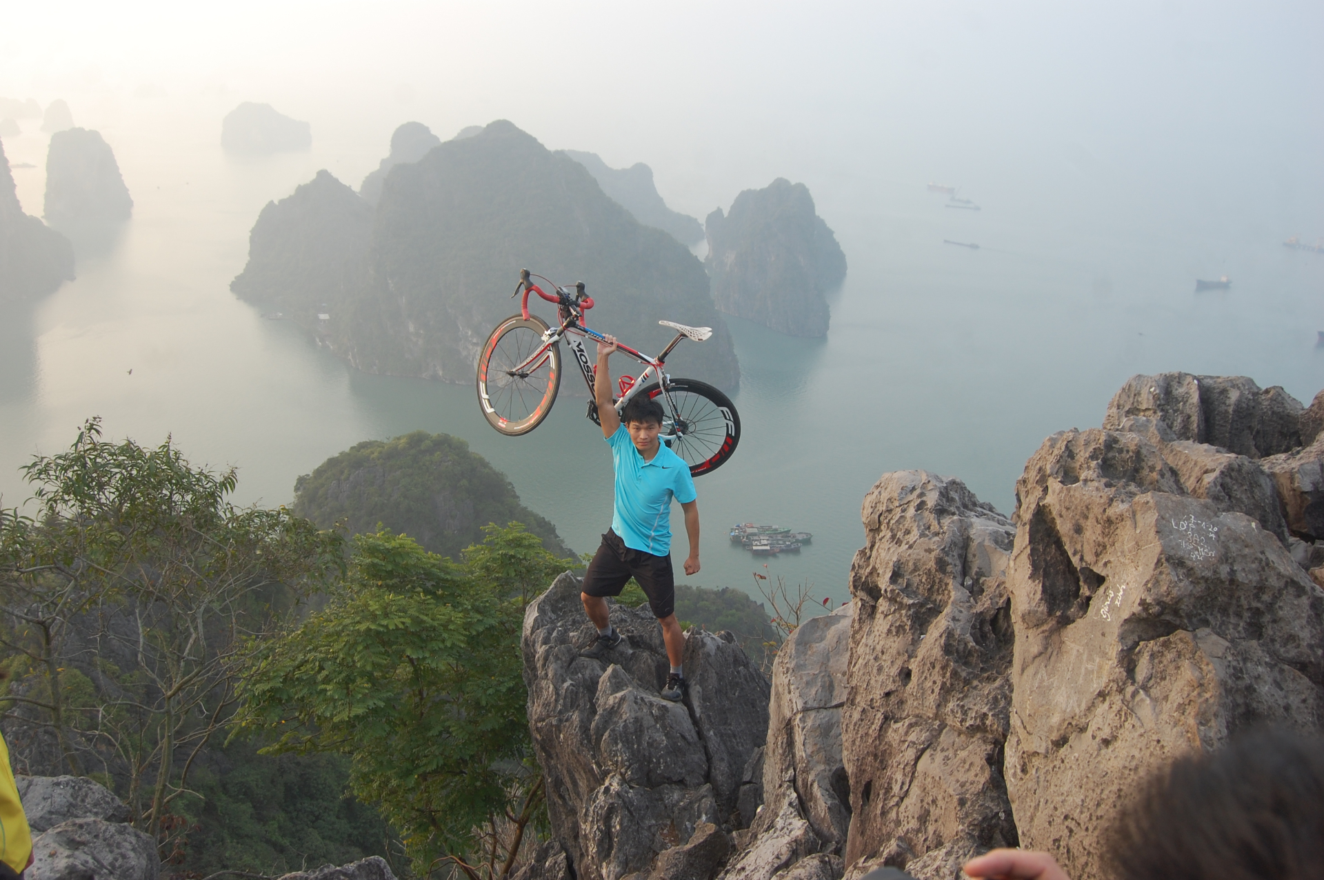 Bạn đồng hành nâng xe đạp trên đỉnh Núi Bài Thơ nhìn ra Vịnh Hạ Long
